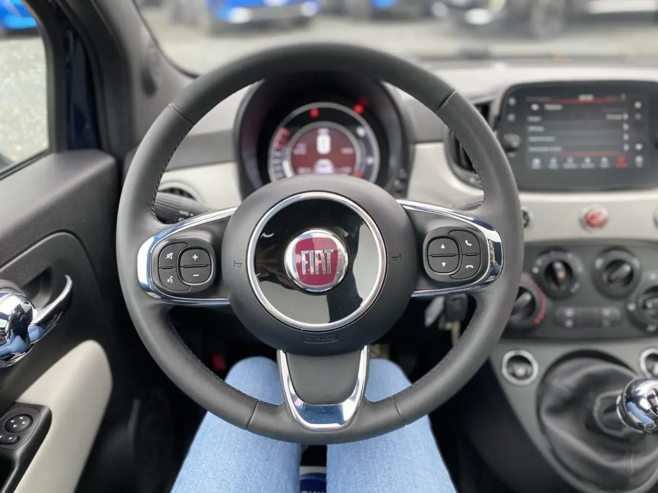 Vue intérieure centrée sur le volant noir et chrome du Fiat 500 2019 avec tableau de bord et levier de vitesses manuel visibles.