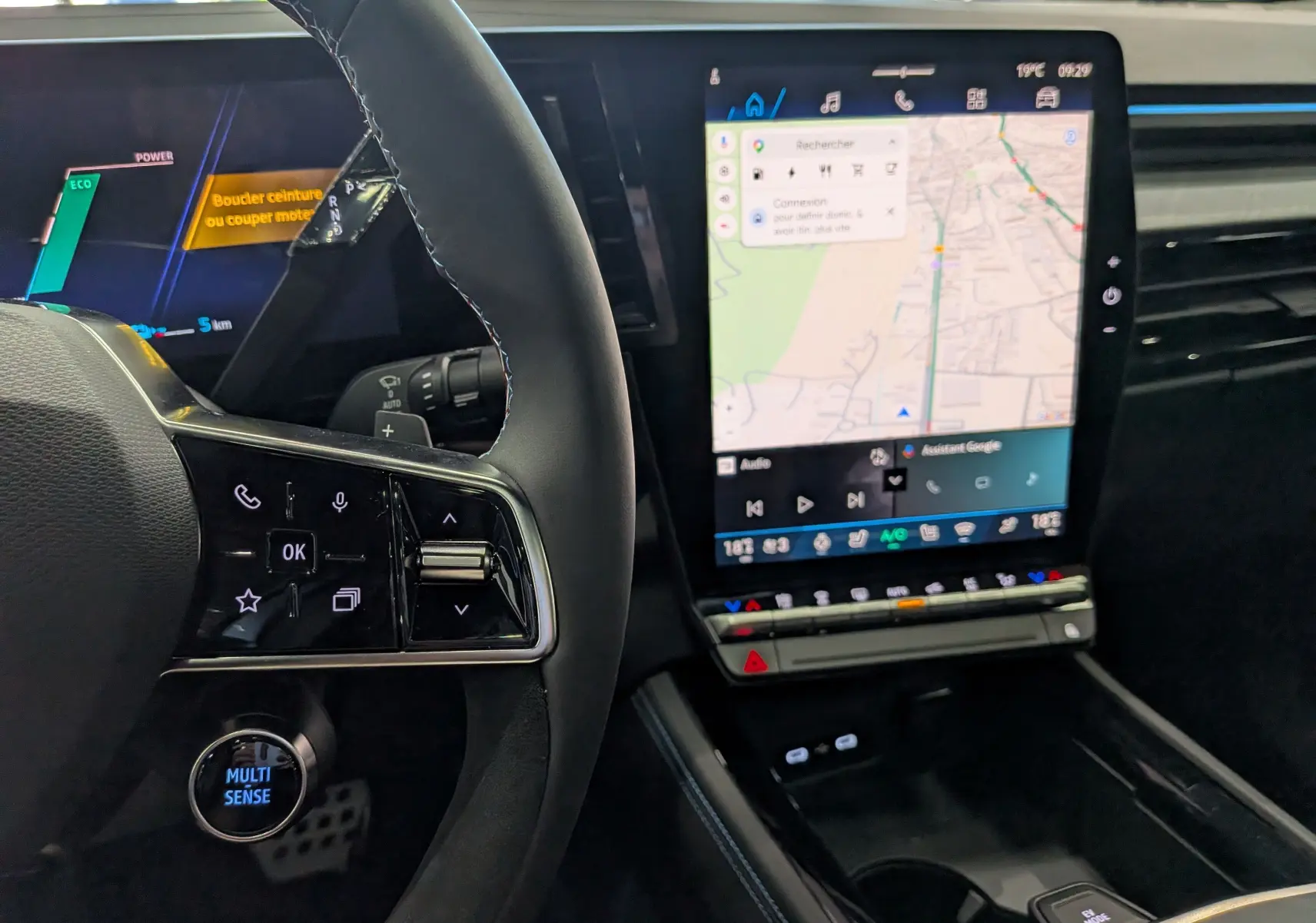 Vue intérieure centrée sur le volant et l’écran tactile vertical du Renault Rafale gris, avec commandes multifonctions et navigation affichée.