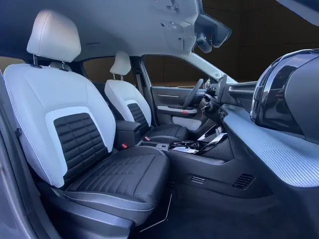 Vue intérieure côté conducteur du Citroën C3 Aircross Hybrid 145 gris Mercury, sièges tissu noir et blanc, tableau de bord moderne.