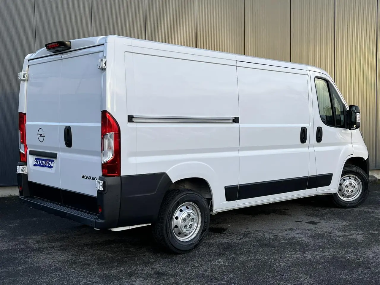 Vue 3/4 arrière droite d’un utilitaire blanc Opel Movano Fourgon avec porte latérale coulissante et rétroviseurs noirs.