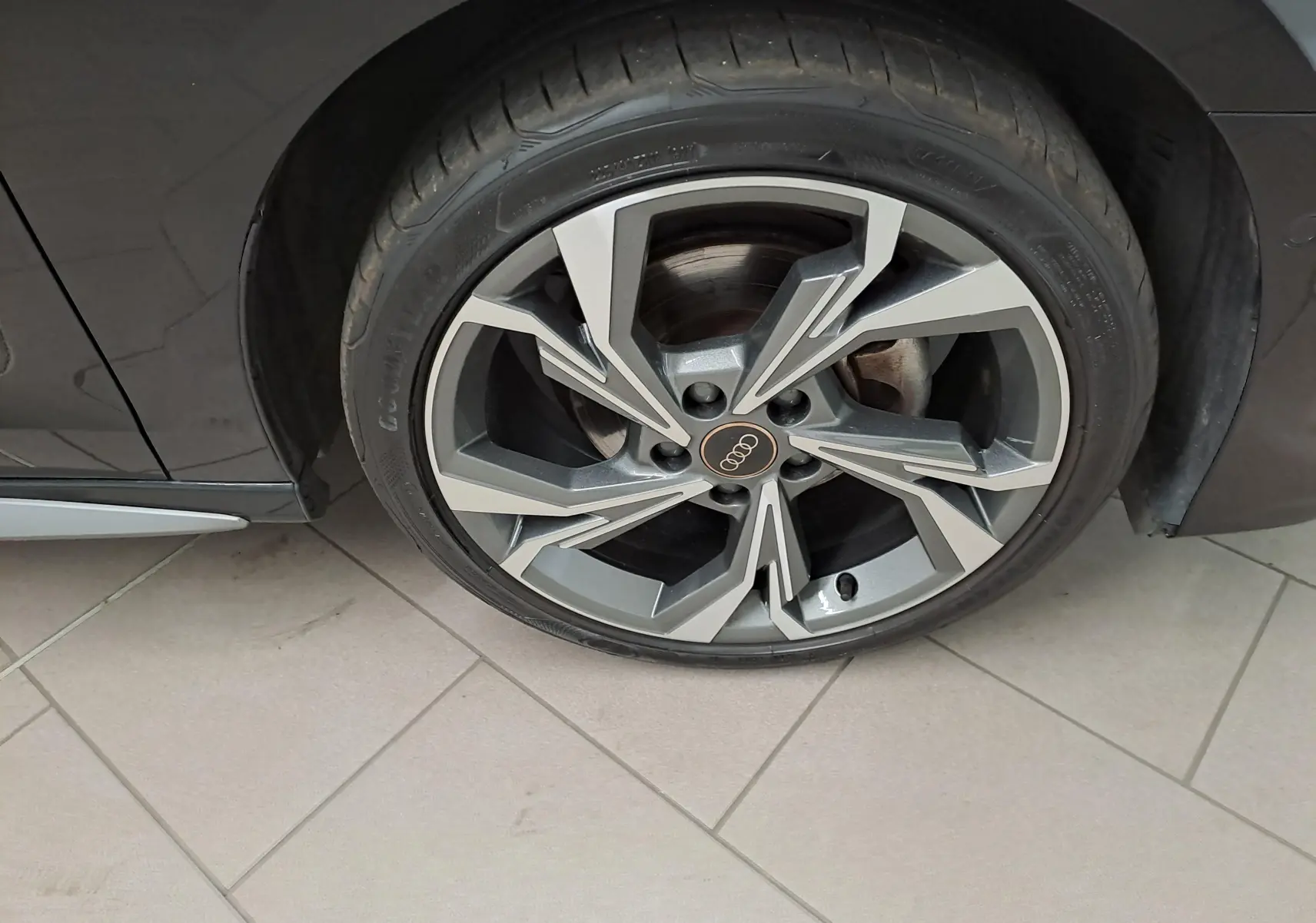 Gros plan sur la roue avant droite d’une Audi A3 Sportback 35 TFSI S Line noire mythic avec jante alliage au design géométrique.