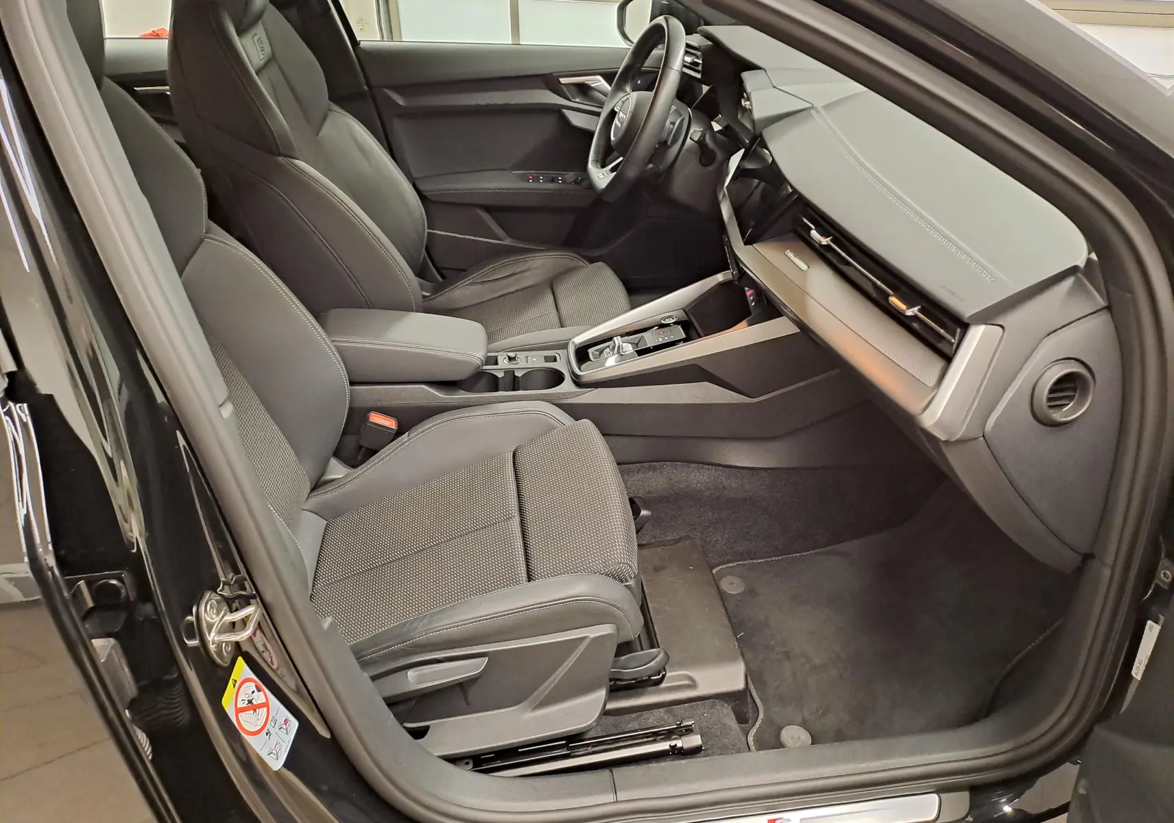 Vue intérieure côté conducteur de l'Audi A3 Sportback 35 TFSI S Line 2023 en Noir Mythic, avec sièges sport et tableau de bord moderne.