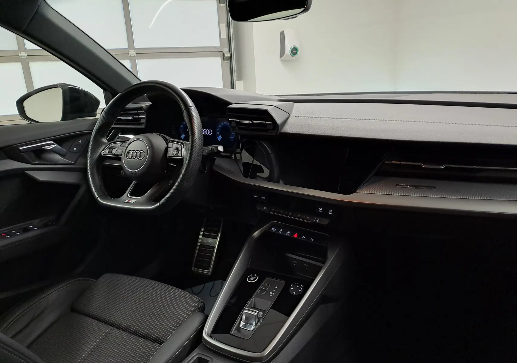 Intérieur noir de l'Audi A3 Sportback 35 TFSI 150 S Line 2023, vue côté conducteur sur le tableau de bord et volant.