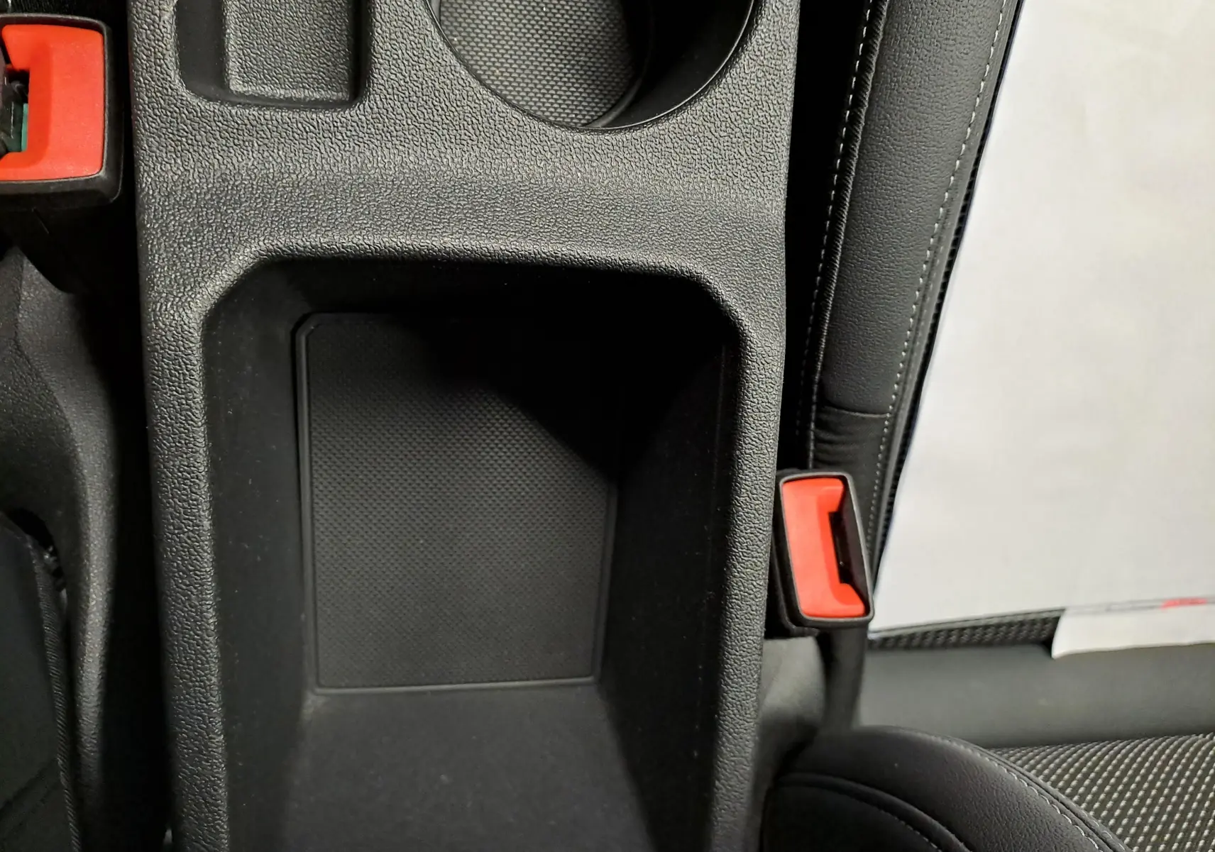 Gros plan intérieur sur le rangement central et la ceinture de sécurité rouge de l'Audi A3 Sportback Noir Mythic 2023.