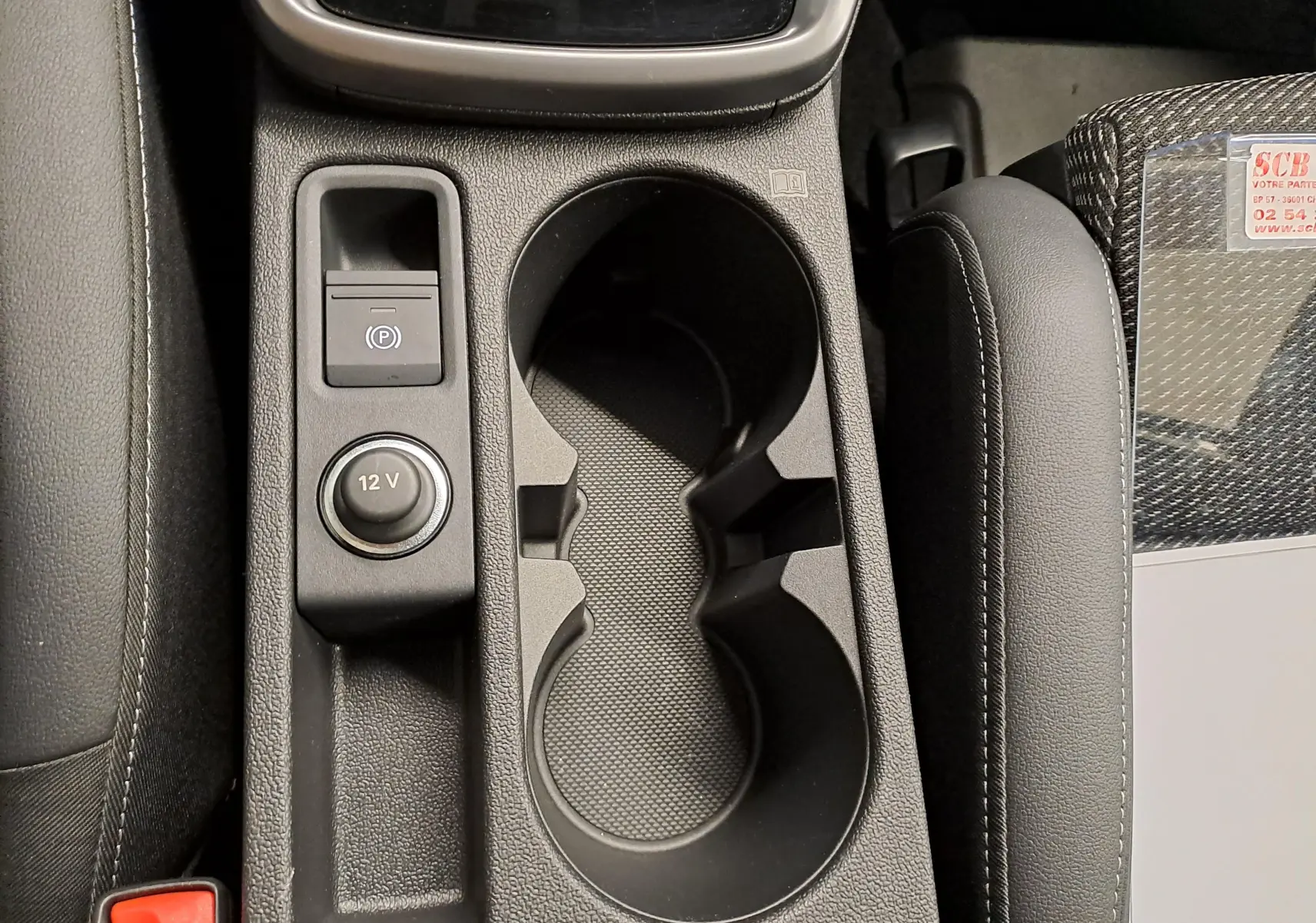 Gros plan sur la console centrale de l’Audi A3 Sportback 35 TFSI S Line 2023, avec porte-gobelets et bouton 12V.
