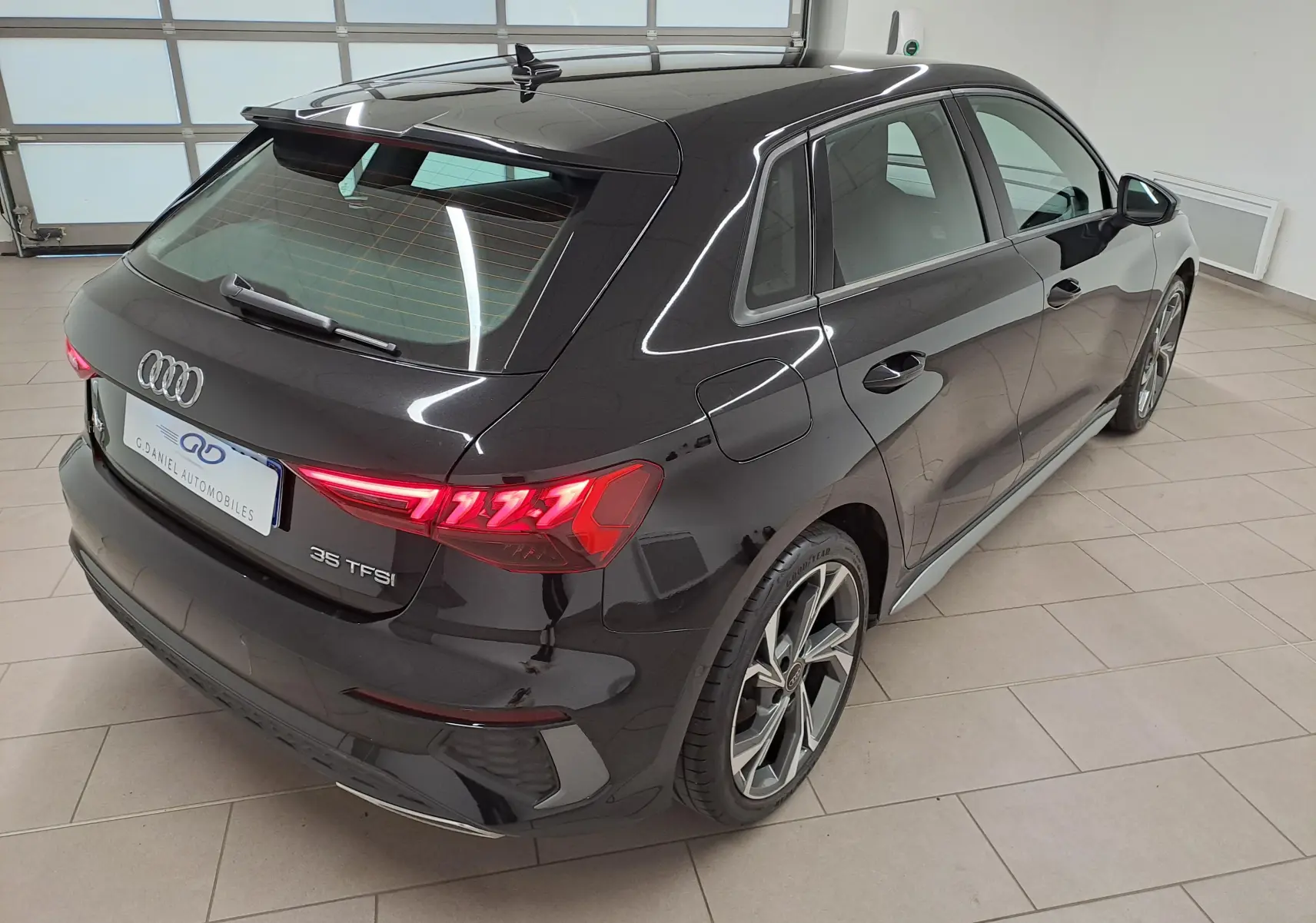Audi A3 Sportback 35 TFSI S Line noir mythic vue 3/4 arrière droit, avec feux arrière LED et jantes alliage distinctives.