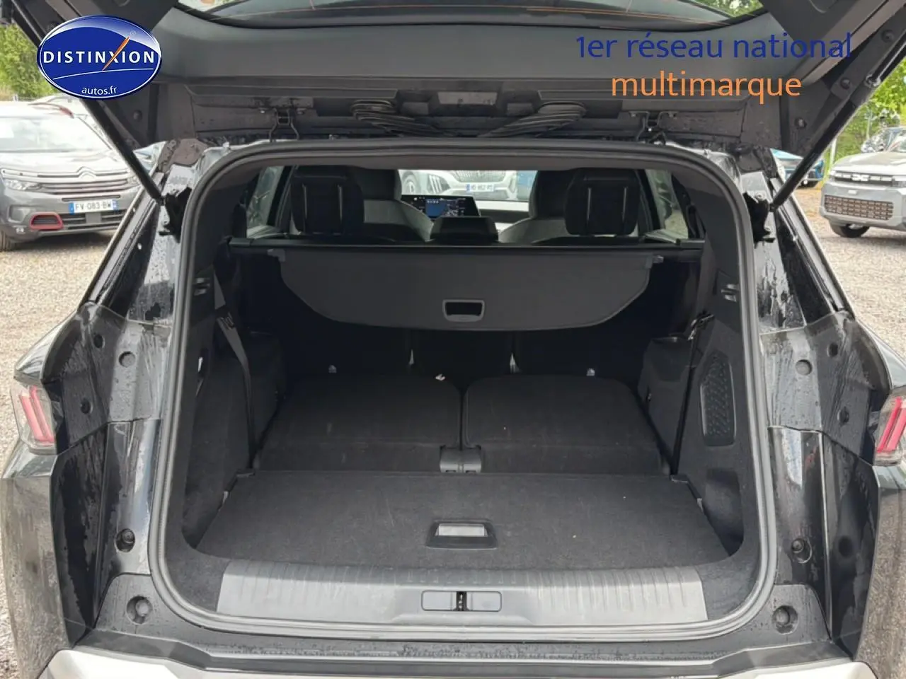Coffre ouvert d’un Peugeot 5008 noir vu de l’arrière, banquette arrière rabattue pour un grand espace de chargement.