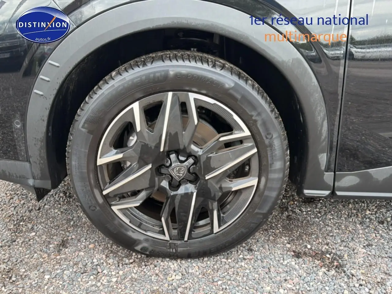 Gros plan sur la roue avant gauche noire du Peugeot 5008 Hybrid 145 allure e-dcs6 avec jante alu design.