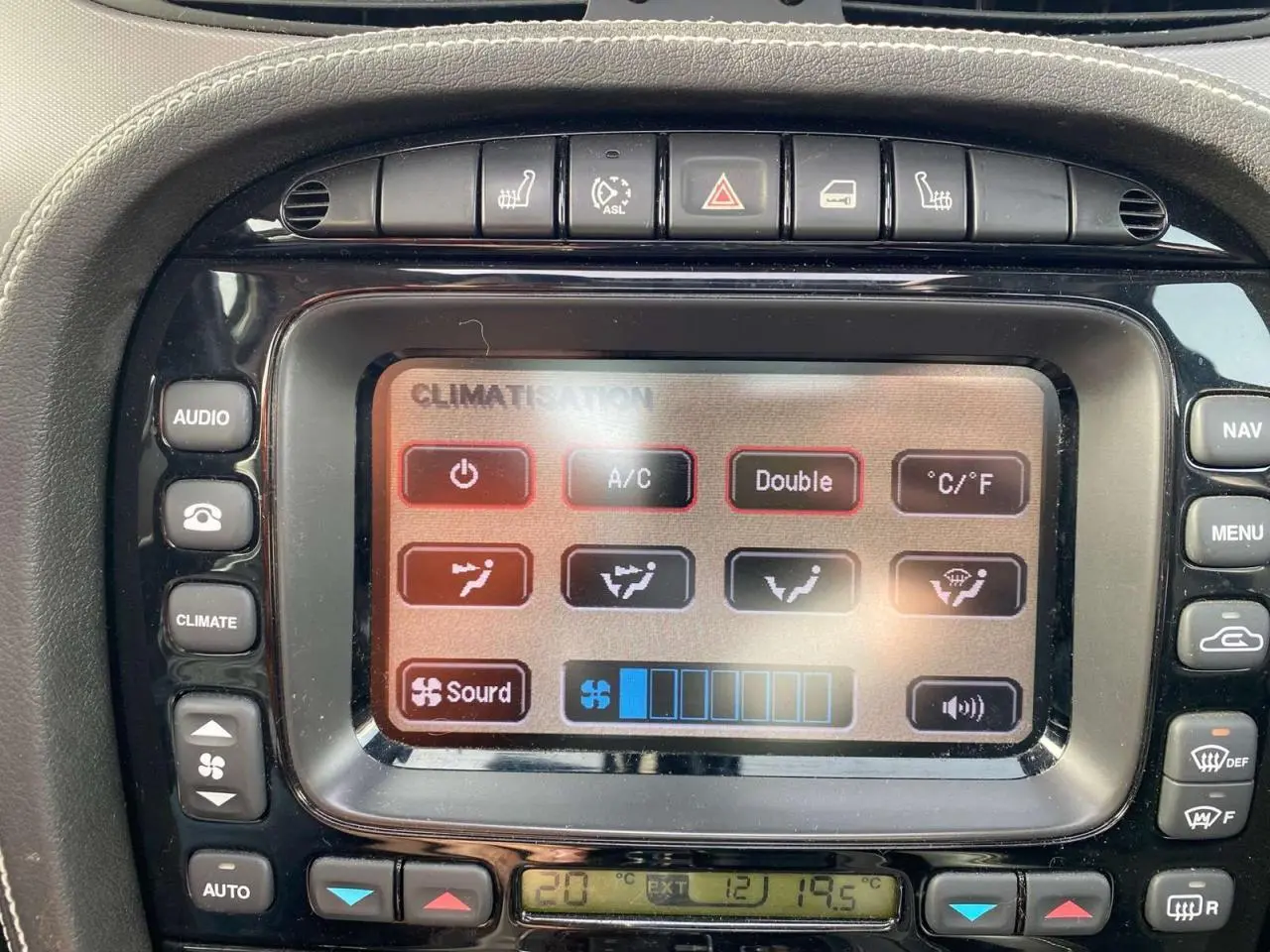 Gros plan sur l'écran tactile du centre multimédia de la Jaguar XJ noire, affichant les commandes de climatisation.