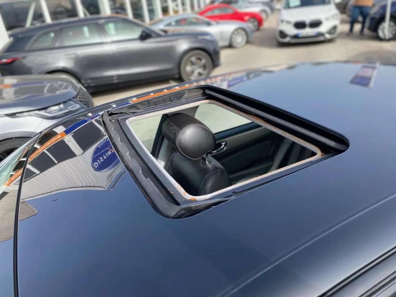 Toit ouvrant ouvert vu de dessus sur une Jaguar XJ noire, avec appui-tête avant visible à l'intérieur.