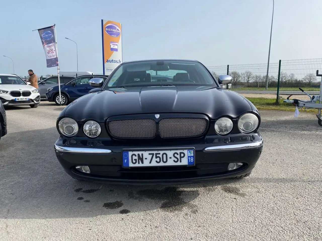 Vue avant d'une Jaguar XJ noire de 2006 avec calandre chromée et phares ronds, stationnée en extérieur.