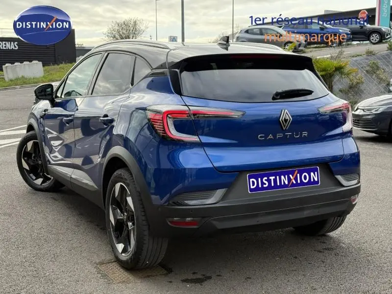 Vue 3/4 arrière d'un Renault Captur 2025 Bleu Iron/Noir Étoilé avec vitres teintées et jantes noires distinctives.