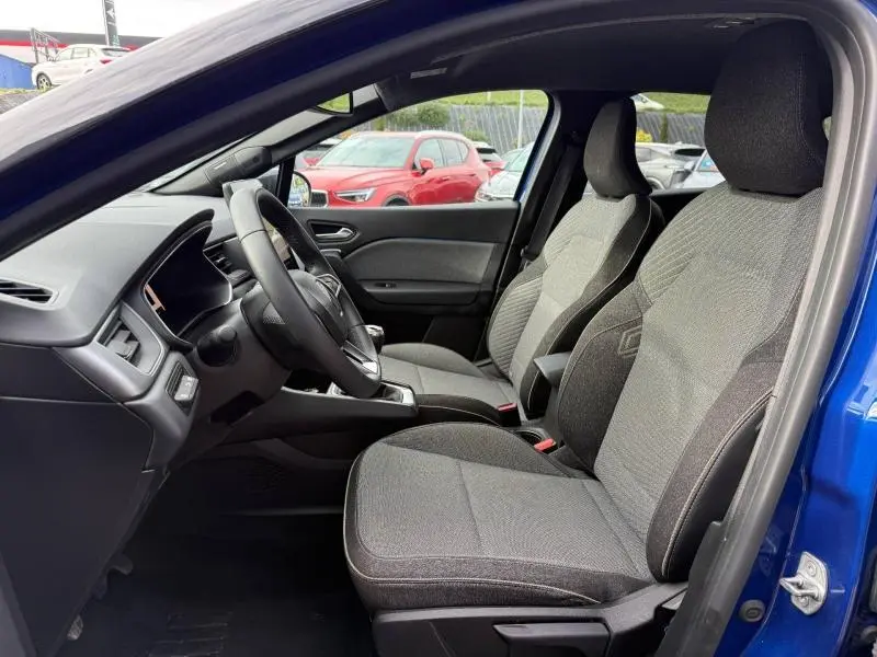 Vue intérieure côté conducteur du Renault Captur 2025 Bleu Iron, sièges gris et volant avec boîte manuelle visible.