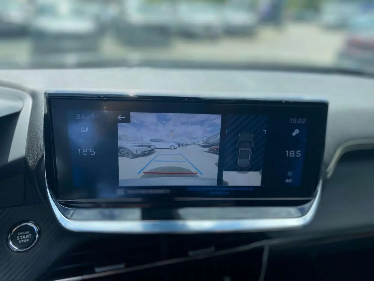 Écran tactile du Peugeot 2008 gris foncé montrant l’aide au stationnement arrière avec vue caméra et capteurs.