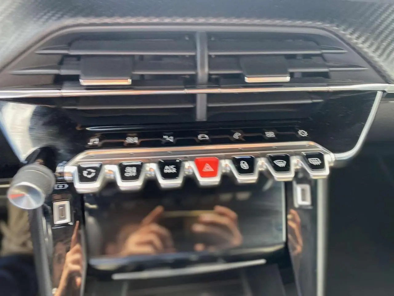 Vue rapprochée de la console centrale du Peugeot 2008, boutons de commande et écran tactile noir brillant.
