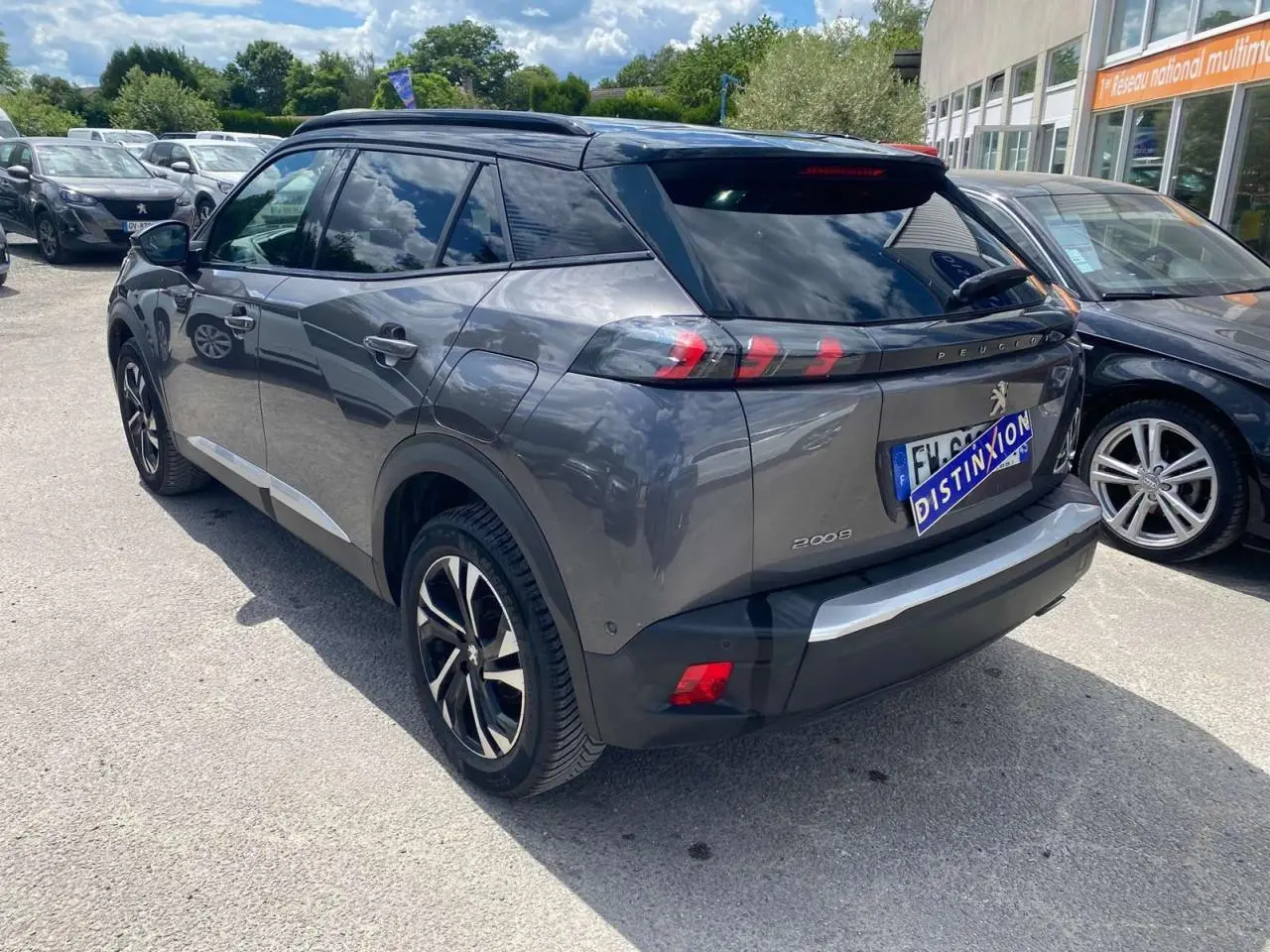 Peugeot 2008 gris foncé vue 3/4 arrière droit, jantes alliage bi-ton et toit noir brillant visible.