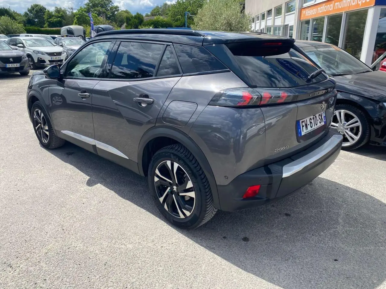 Vue 3/4 arrière droite d'un Peugeot 2008 gris foncé avec jantes alliage bicolores et toit noir brillant.