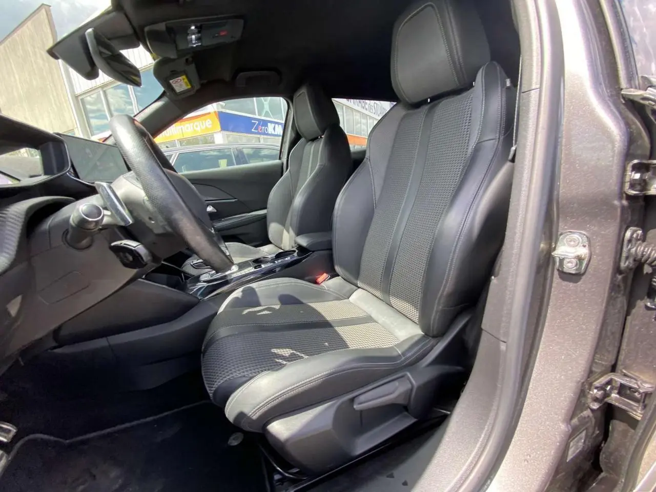 Vue intérieure côté conducteur du Peugeot 2008 2021, sièges en tissu et cuir noir avec surpiqûres grises.