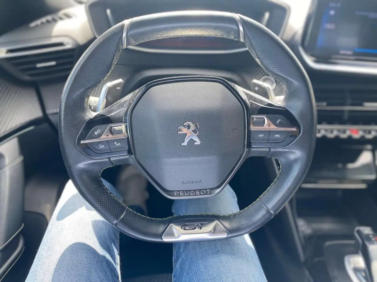 Vue rapprochée du volant cuir noir GT du Peugeot 2008 gris foncé, avec commandes intégrées et logo central.