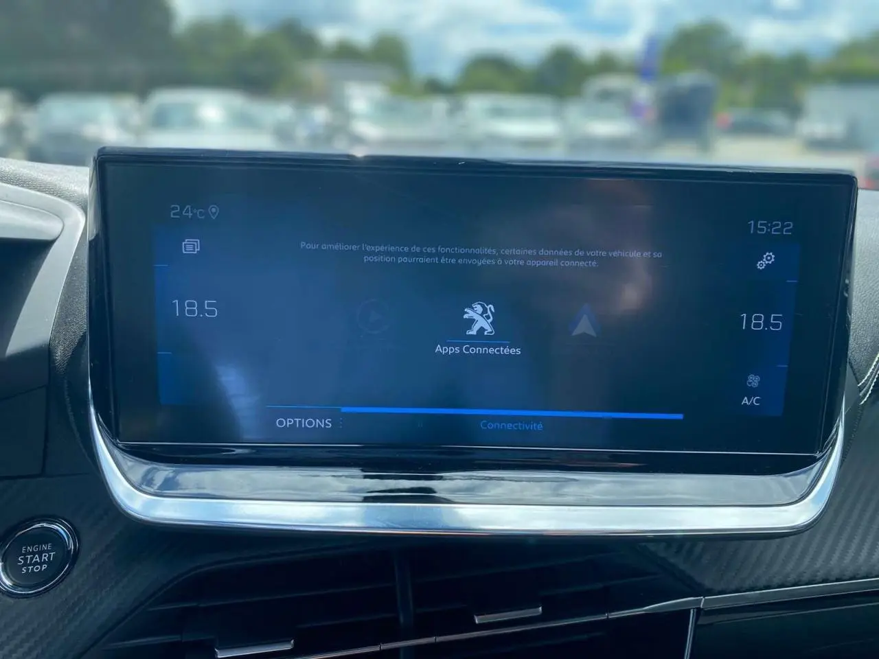 Vue rapprochée de l’écran tactile central du Peugeot 2008 gris foncé, affichant les options de connectivité et la climatisation.