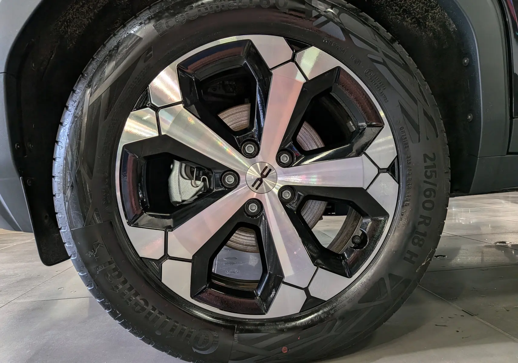 Gros plan sur la roue avant droite du Dacia Bigster noir nacré, mettant en valeur la jante bi-ton argent et noir au design moderne.