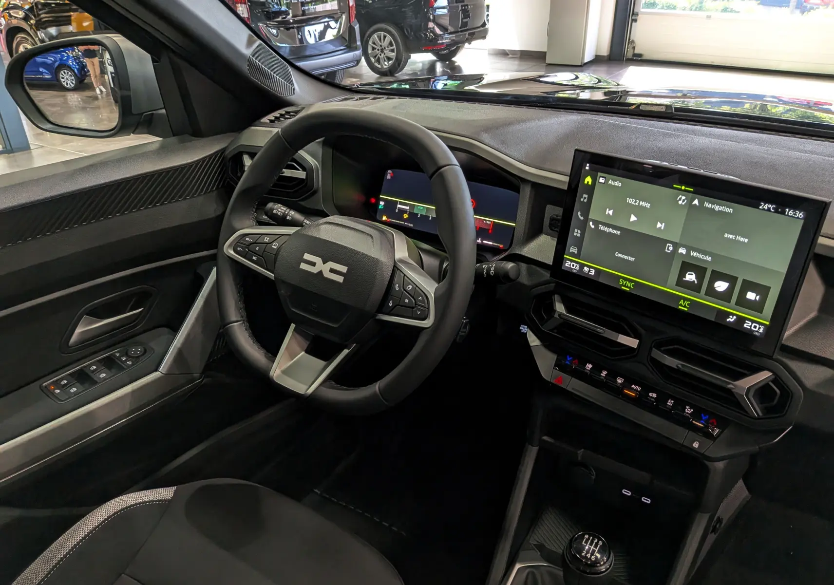 Vue intérieure côté conducteur du Dacia Bigster noir nacré 2026, avec volant multifonction et écran tactile central allumé.