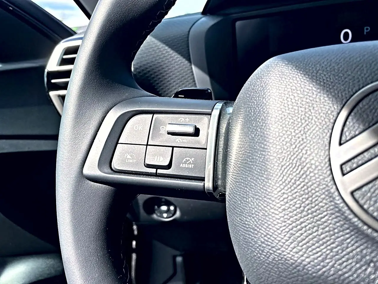 Gros plan sur le volant cuir noir de la Citroën C4 X 2025, avec commandes intégrées côté gauche visibles.