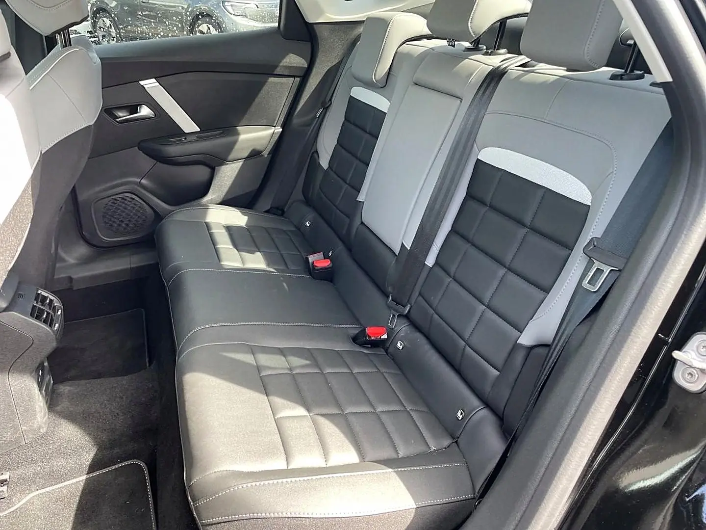 Vue côté droit de la banquette arrière bi-ton noir et gris du Citroën C4 X 1.2 hybride 2025 avec ceinture et appuie-têtes visibles.