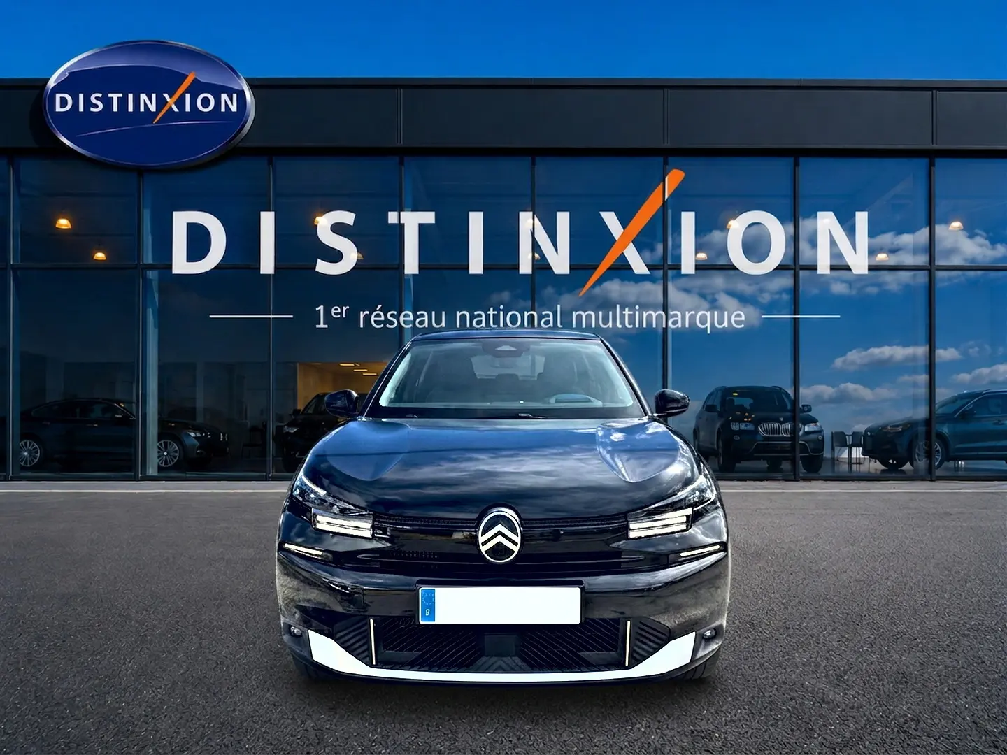 Vue avant d'une Citroën C4 X noire 2025, avec logo distinctif et phares LED fins, devant une vitrine Distinxion.