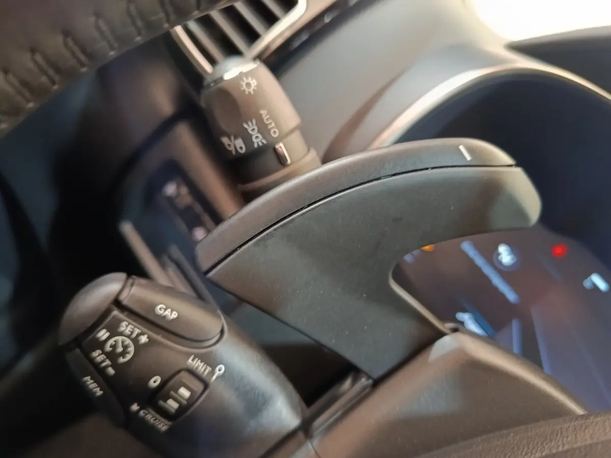 Gros plan sur la commande au volant du Citroën C5 Aircross noir, avec affichage digital flou en arrière-plan.