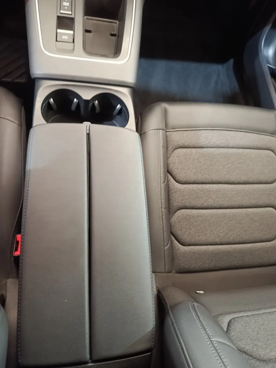 Vue rapprochée de l'intérieur du Citroën C5 Aircross 2024, montrant l'accoudoir central noir et le siège conducteur en tissu et cuir.