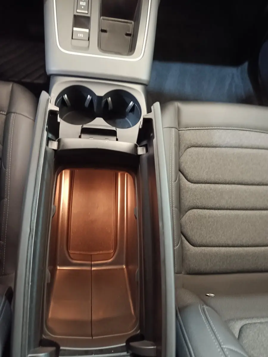 Vue plongeante sur la console centrale noire du Citroën C5 Aircross 2024, avec rangement ouvert et siège tissu gris à côté.