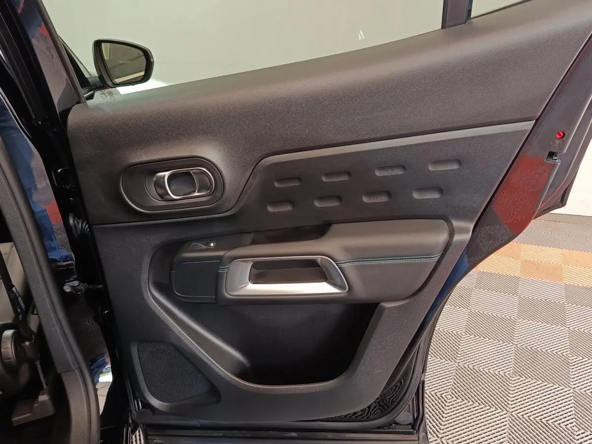 Vue rapprochée de la porte arrière droite noire du Citroën C5 Aircross 2024 avec poignée argentée et surpiqûres bleues.
