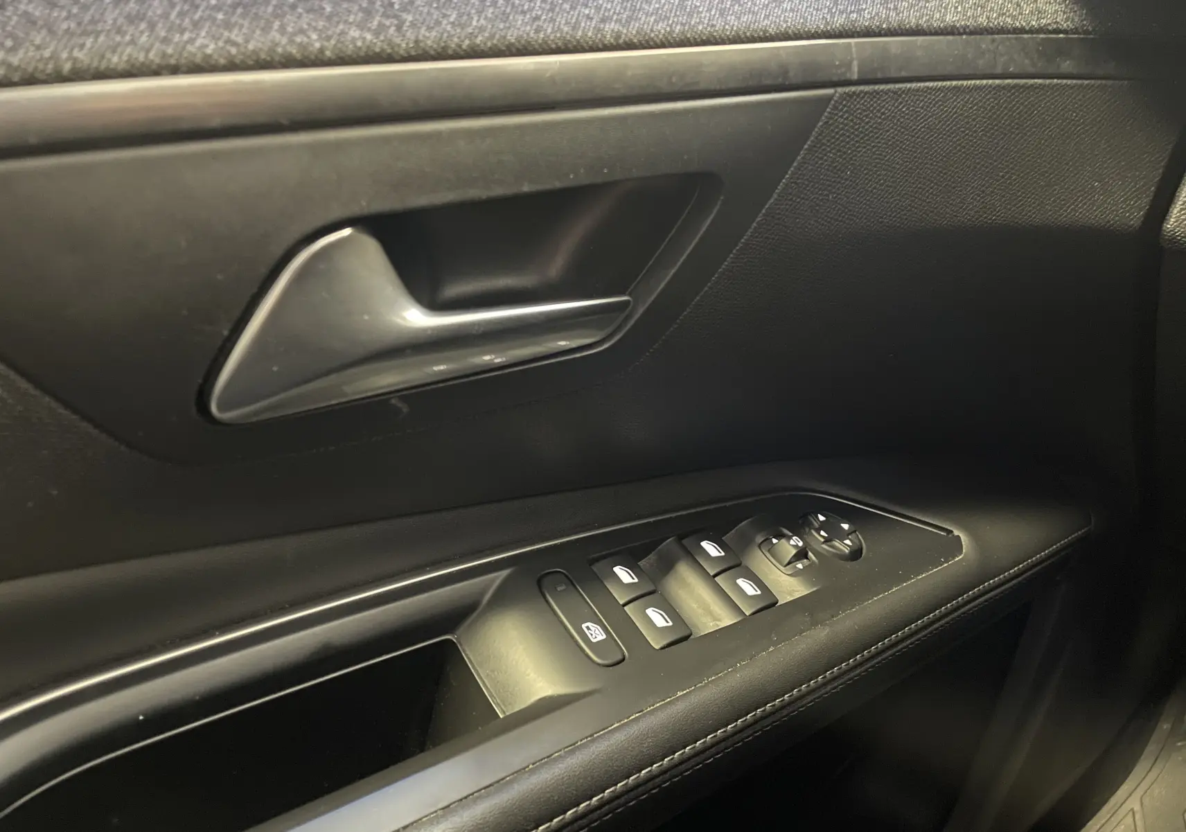 Poignée de porte intérieure côté gauche du Peugeot 5008 blanc nacré avec commandes des vitres et rétroviseurs.