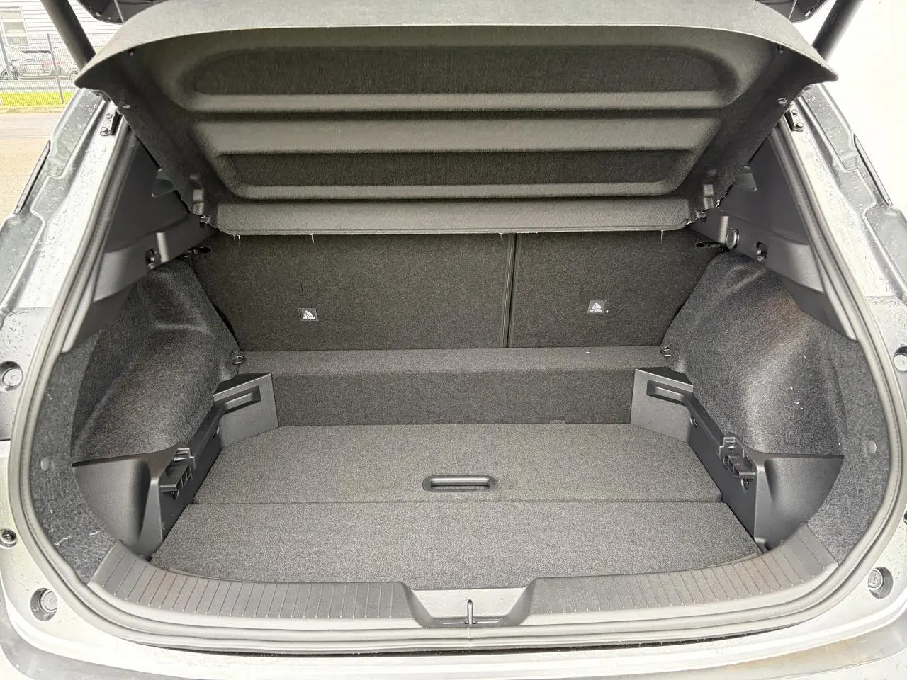 Coffre ouvert vu de l'arrière du Nissan Qashqai III gris foncé, montrant un espace de chargement vide et bien fini.