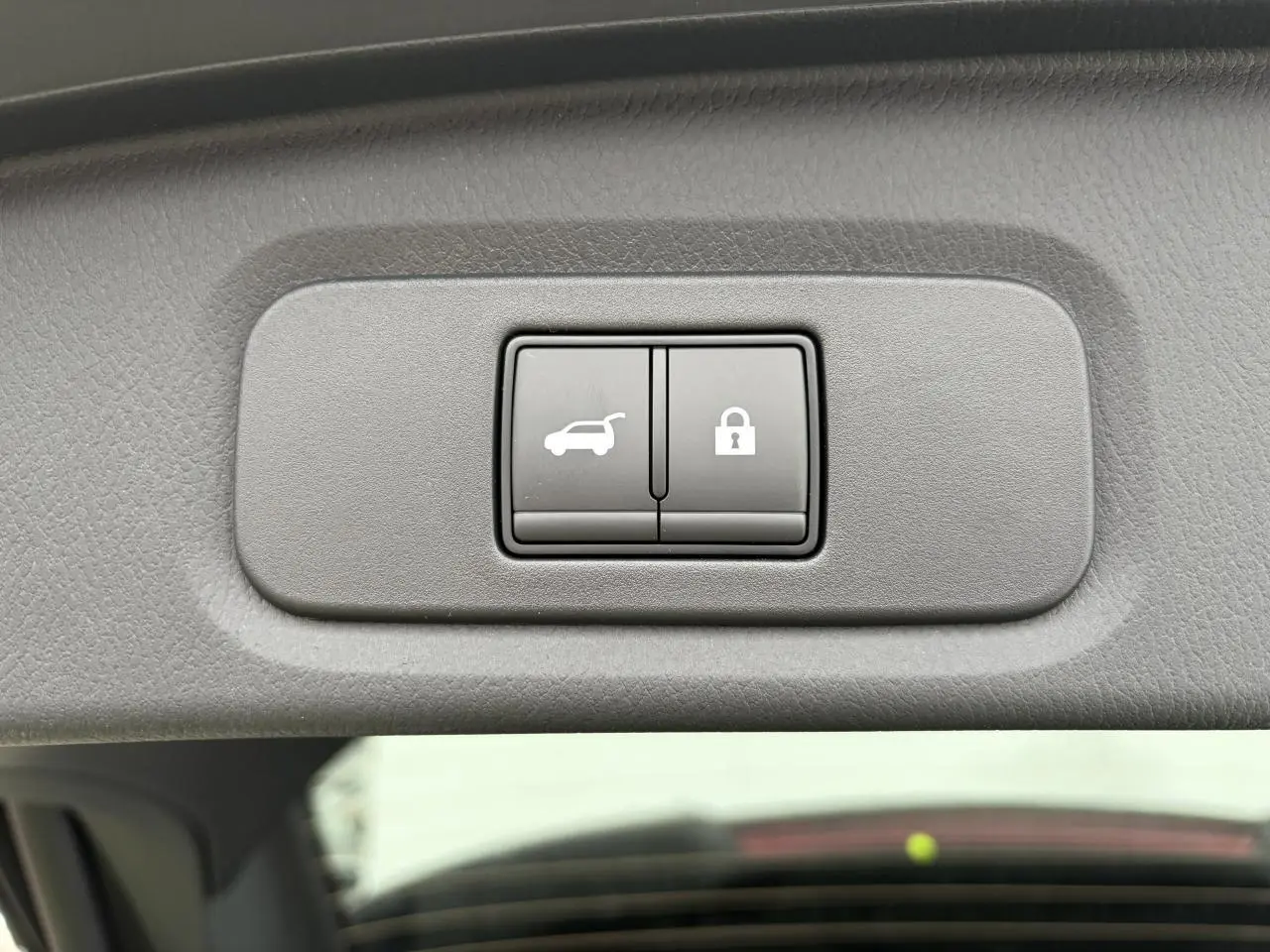 Gros plan sur les boutons d'ouverture électrique et de verrouillage du hayon, intérieur gris du Nissan Qashqai 2025.