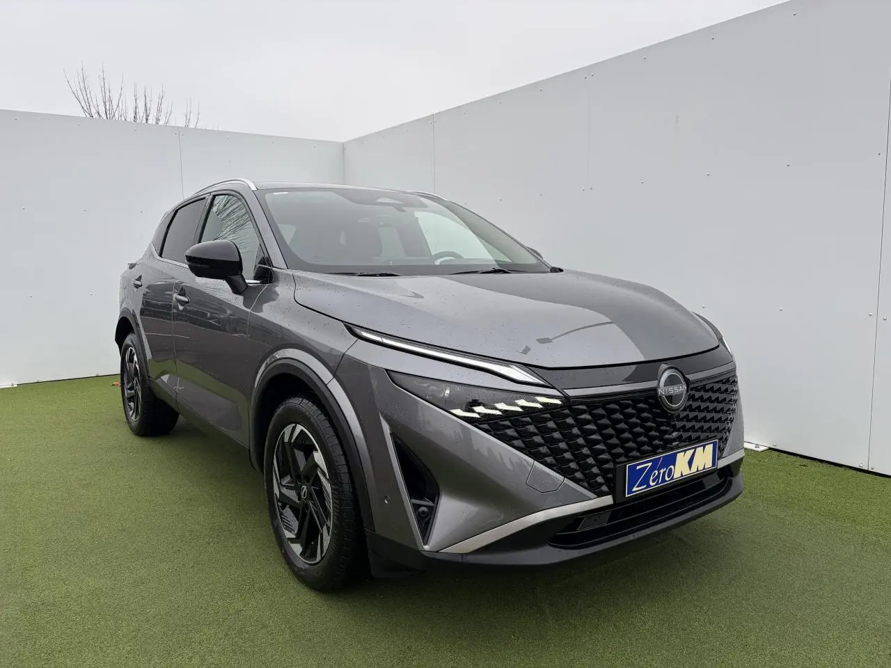 Nissan Qashqai III 1.5 Hybrid E-Power gris foncé, vue 3/4 avant avec calandre noire et jantes alliage 18 pouces.
