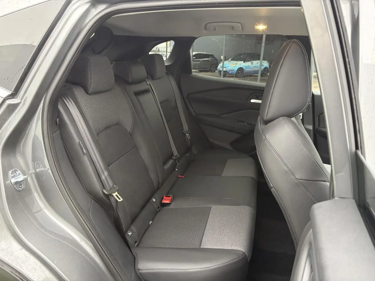 Vue côté gauche sur la banquette arrière mixte tissu et TEP noire du Nissan Qashqai III gris foncé, avec ceinture de sécurité visible.