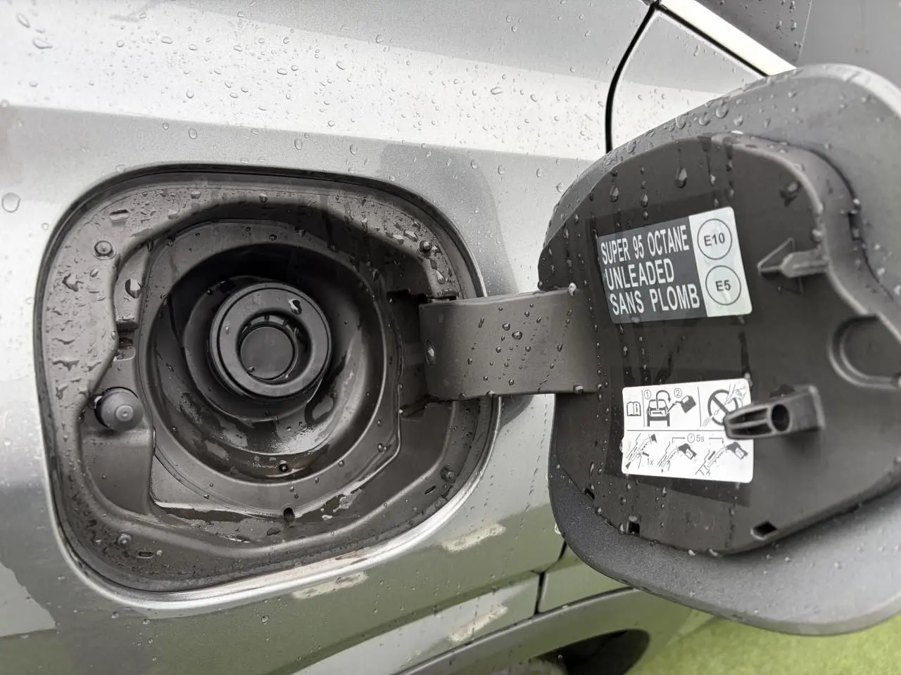 Gros plan sur la trappe à carburant ouverte du Nissan Qashqai 2025 gris foncé métallisé, avec consignes visibles.