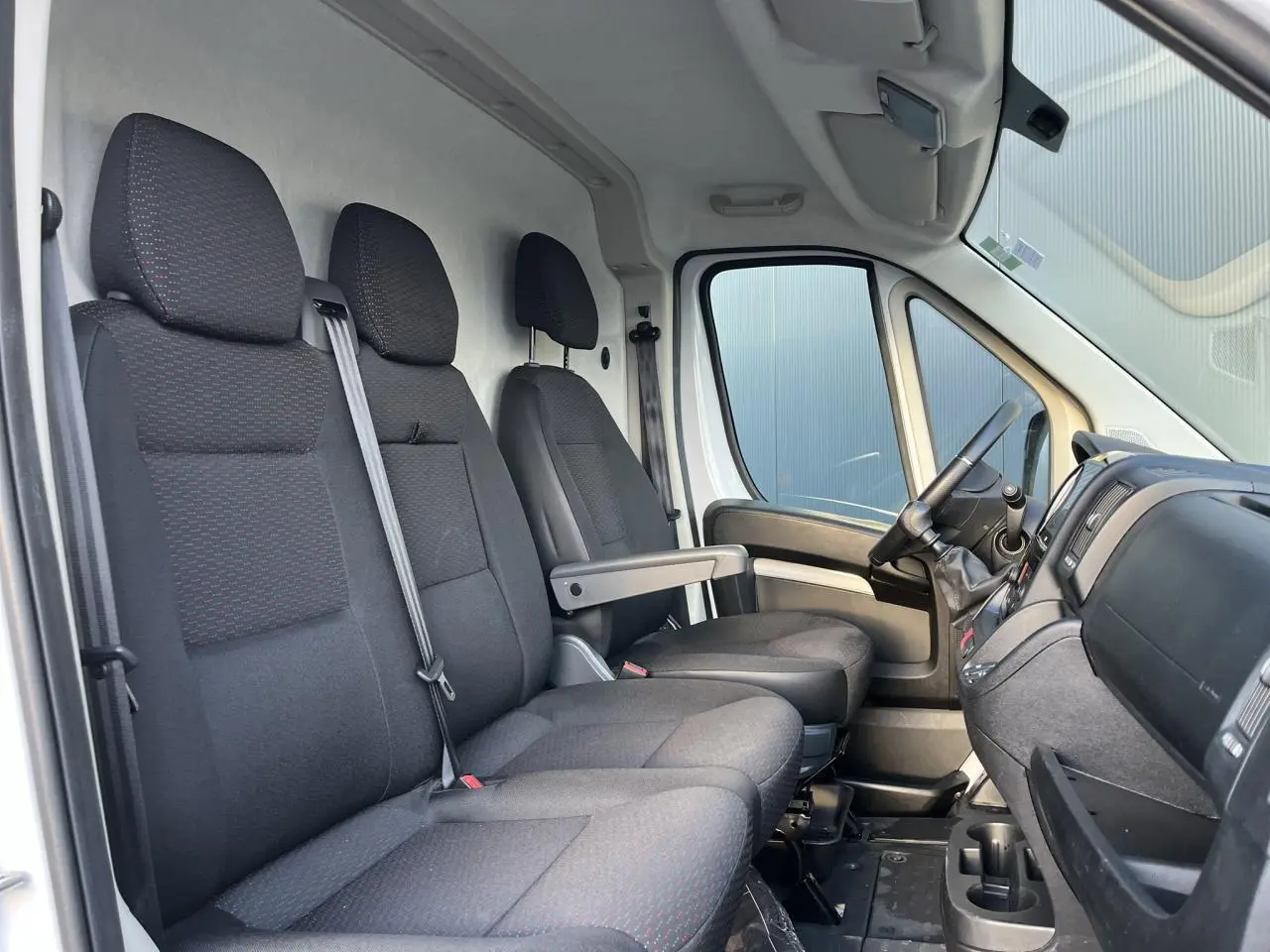 Vue intérieure côté conducteur de l'Opel Movano Fourgon 2024 avec sièges noirs et tableau de bord visible.