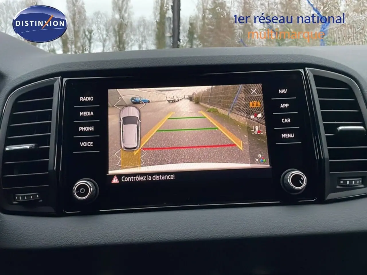 Écran central de la Skoda Karoq gris argent 2025 affichant la caméra de recul avec guidage de trajectoire coloré.