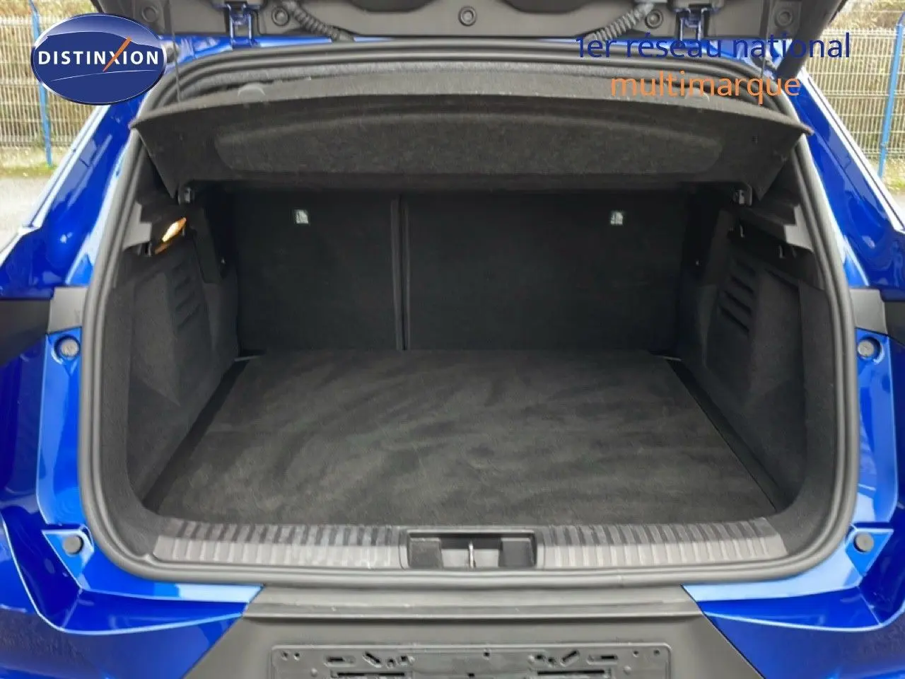 Coffre ouvert vu de l'arrière d'une Renault Symbioz 2025 bleu Iron Metal, espace de chargement vide et propre.