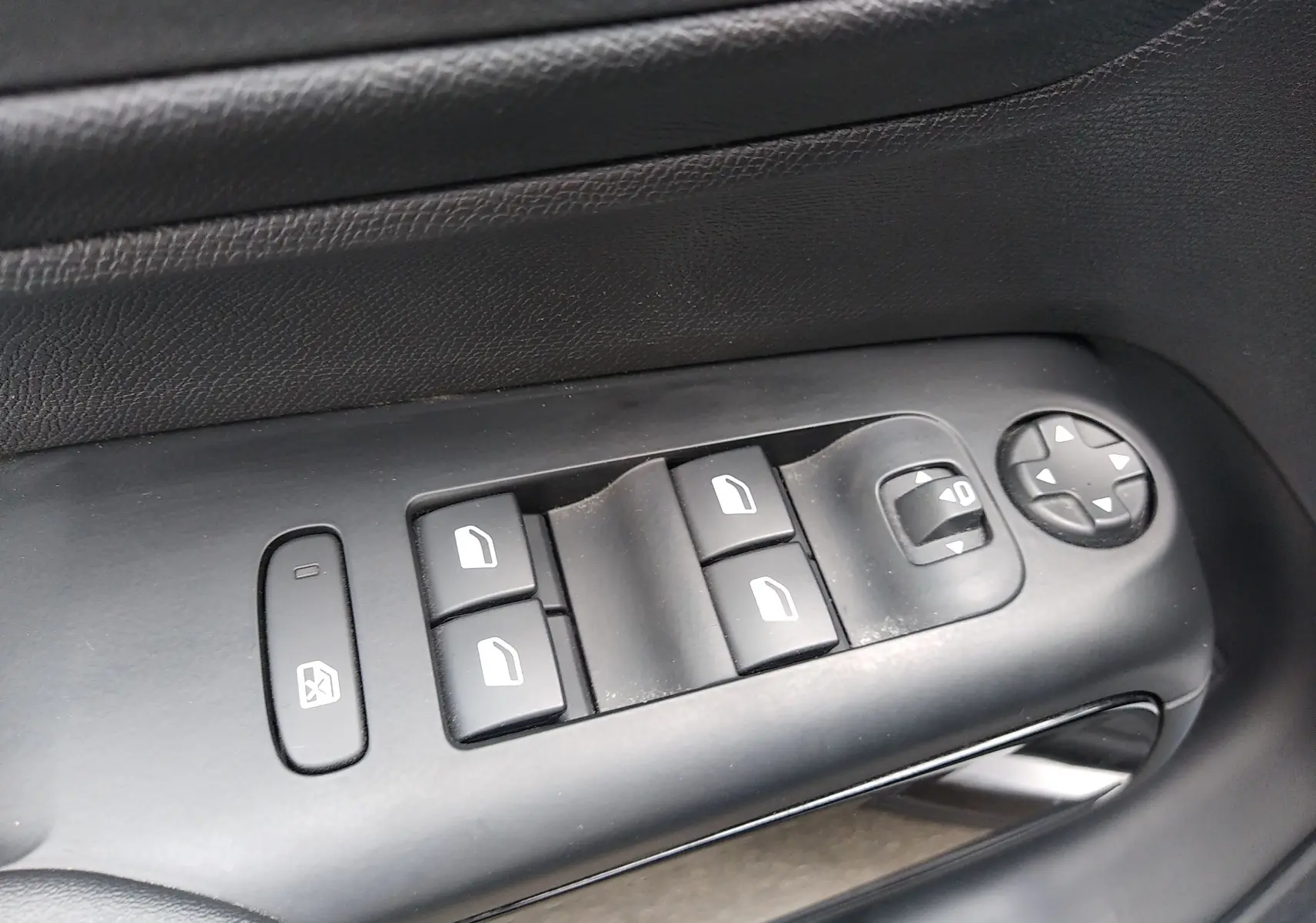 Gros plan sur les commandes de lève-vitres et réglages des rétroviseurs côté conducteur d’un Citroën C5 Aircross gris platinium.