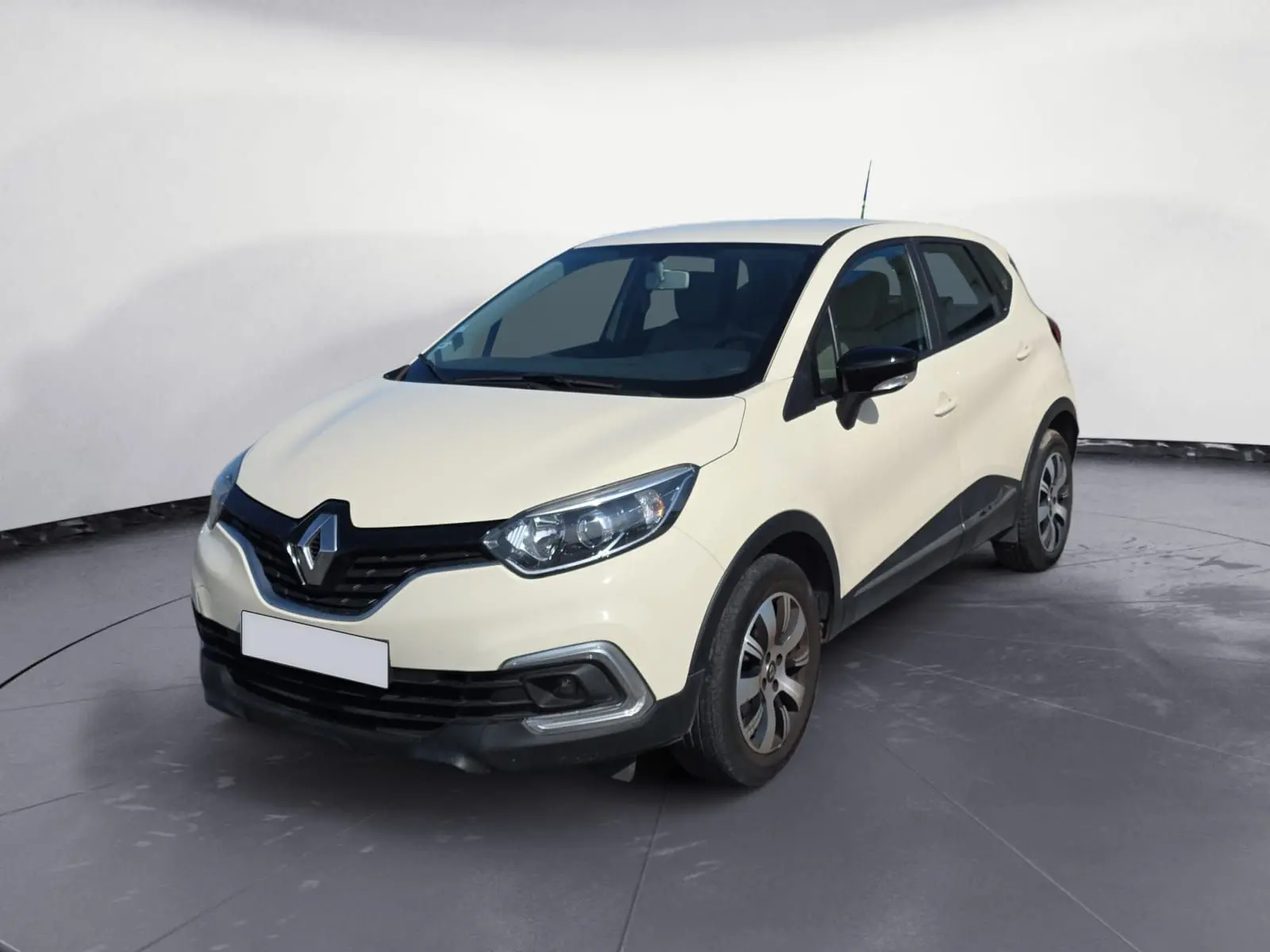 Renault Captur ivoire vue 3/4 avant droit sur parking, avec jantes alliage et calandre noire distinctive.