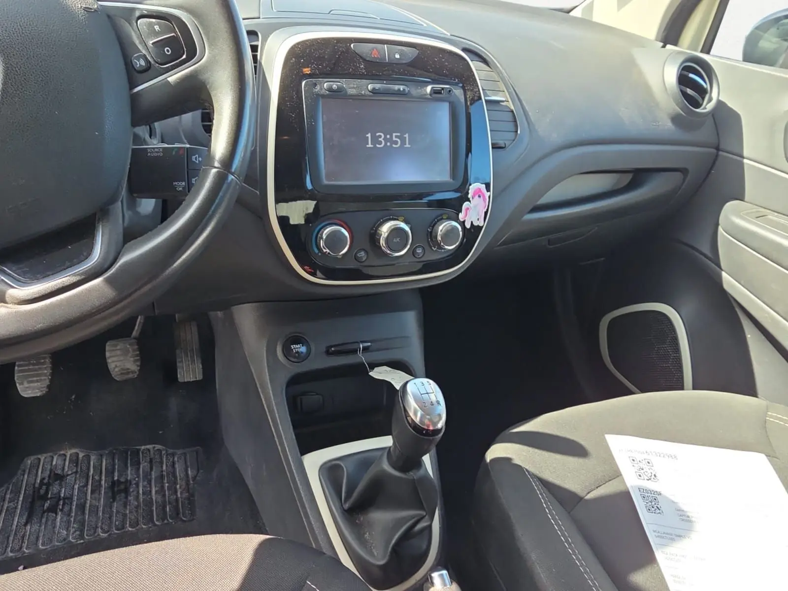 Vue rapprochée de la console centrale noire avec écran tactile et commandes de climatisation du Renault Captur ivoire 2018.