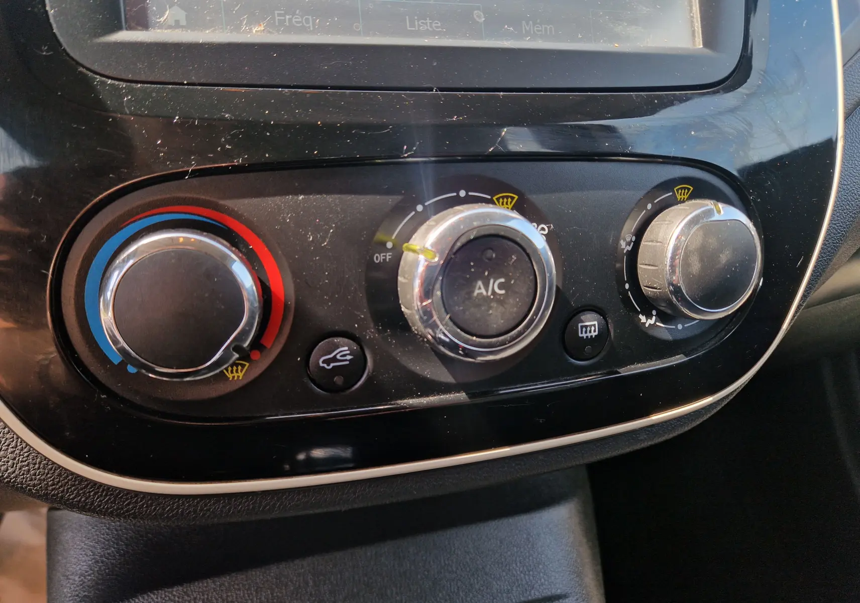 Gros plan sur les commandes de climatisation noires du Renault Captur ivoire, avec réglages de température et ventilation visibles.