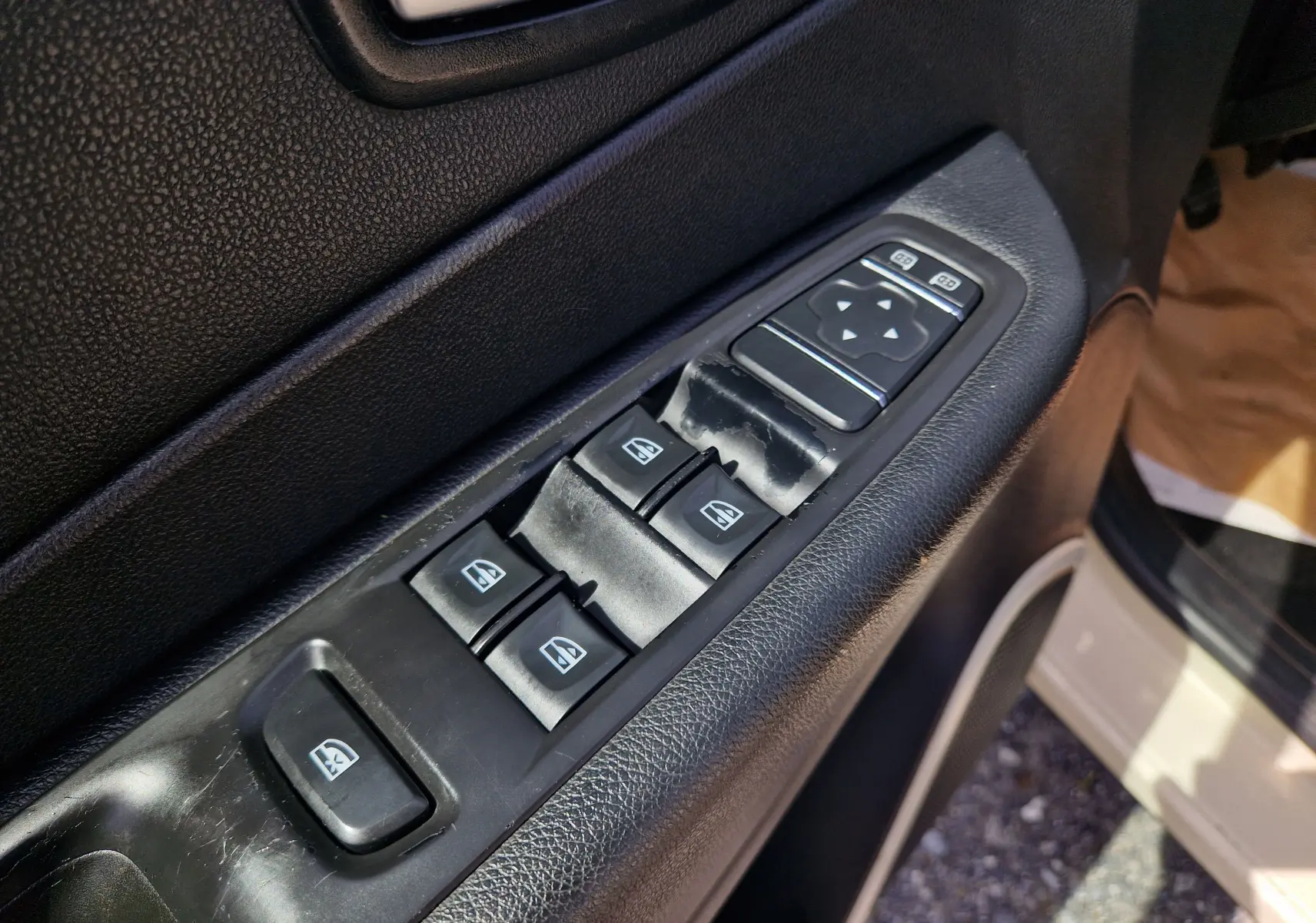 Gros plan sur les commandes des vitres électriques côté conducteur d’un Renault Captur ivoire, intérieur noir.
