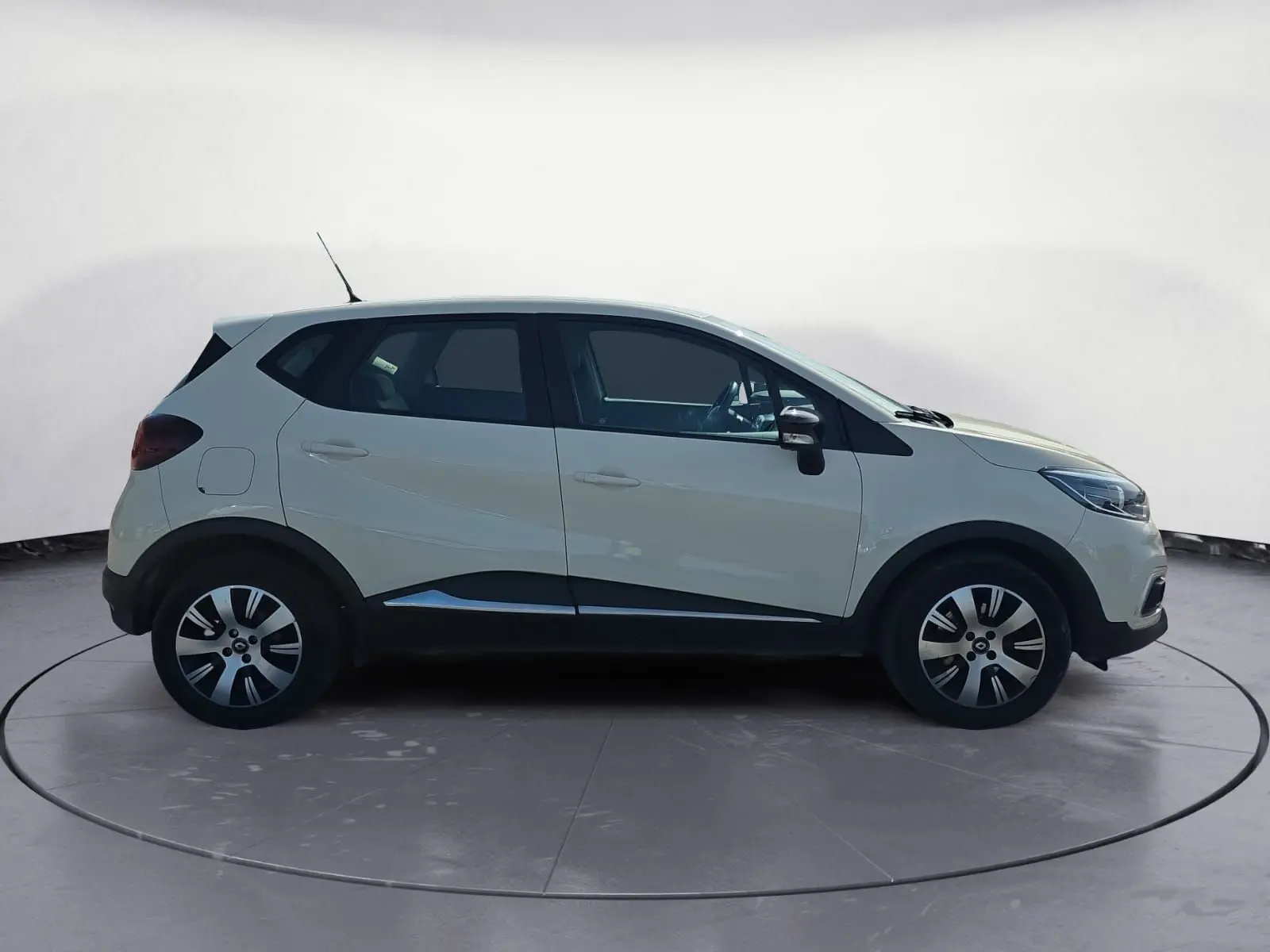 Renault Captur ivoire vue 3/4 arrière droit sur sol gravillonné avec jantes alliage et détails noirs contrastants.