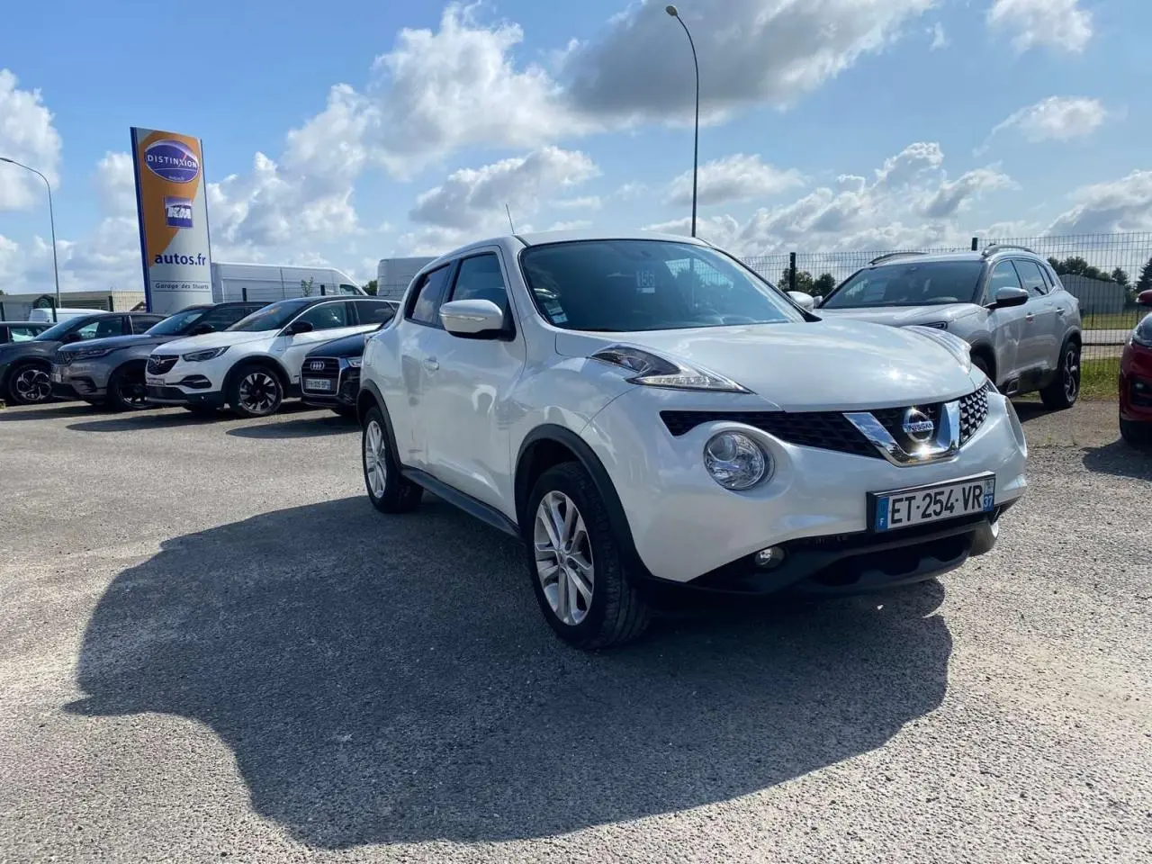 Nissan Juke blanc vue 3/4 avant droit, avec jantes alliage et projecteurs antibrouillard visibles.