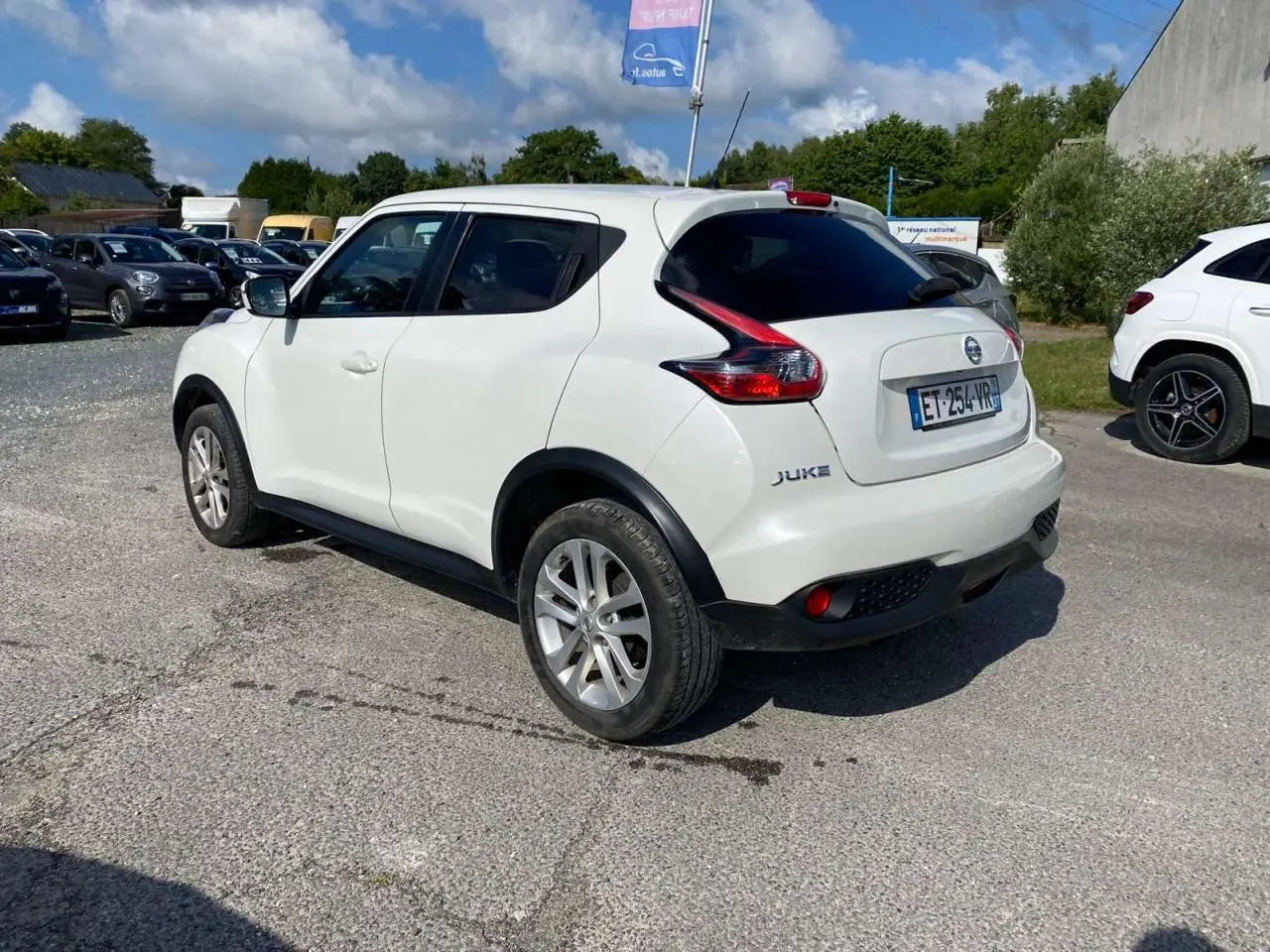 Nissan Juke blanc vue 3/4 arrière droit, jantes alliage 17 pouces et vitres arrière surteintées.